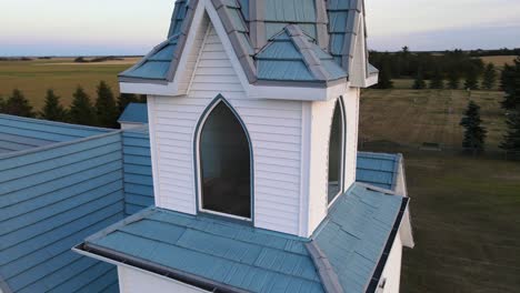 The-bell-inside-a-pristine-white-steeple-of-a-wooden-countryside-church-in-rural-Alberta,-Canada-at-sunset