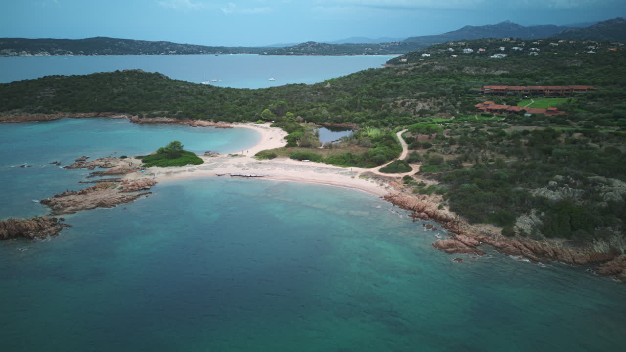 Smooth drone timelapse panning right over Spiaggia Cala Finanza, Sardinia — turquoise waters, sandy beach kept centered