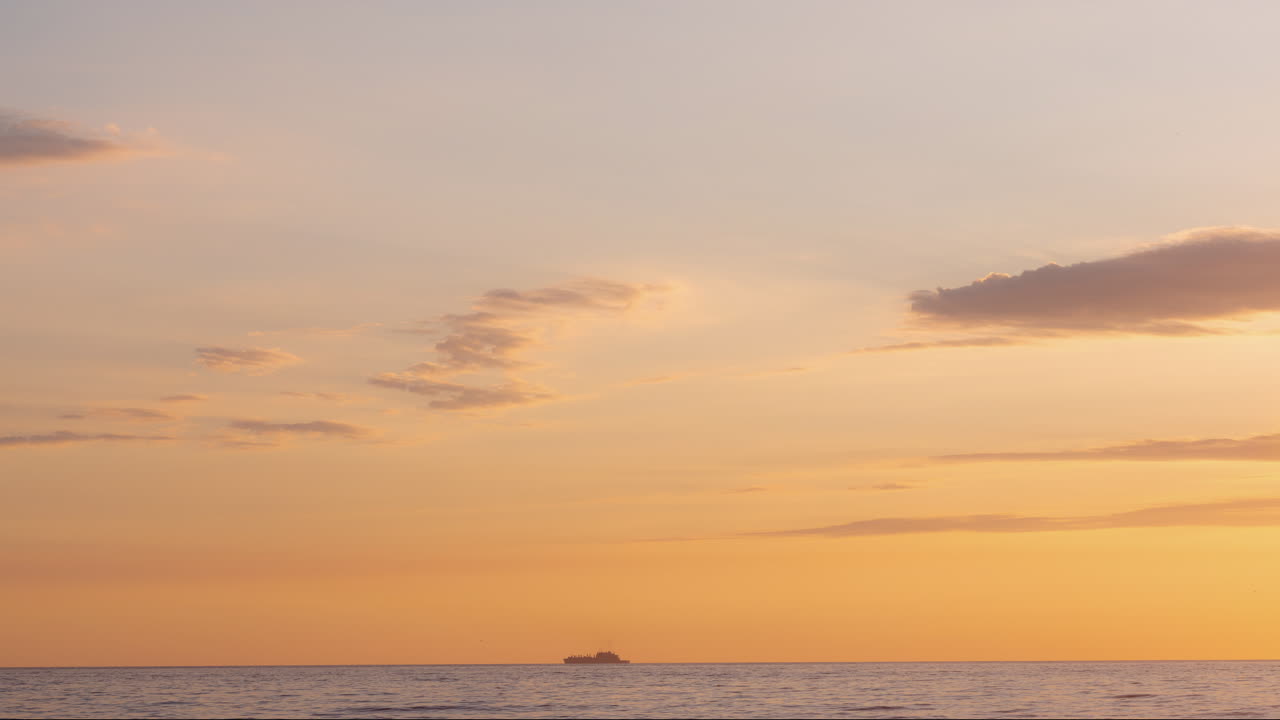 오렌지색 바다를 가로질러 이동하는 화물 선박 해가 지고 작은 구름
