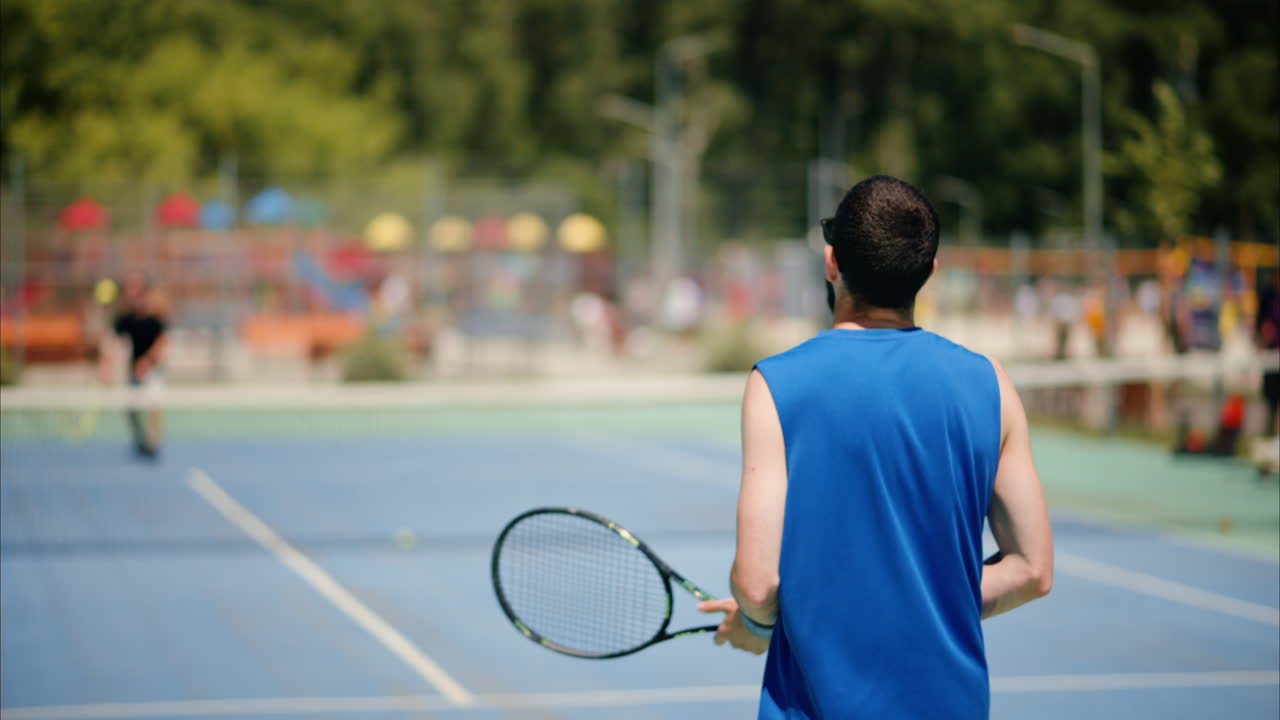 Two men playing tennis on a blue and green court on a sunny day