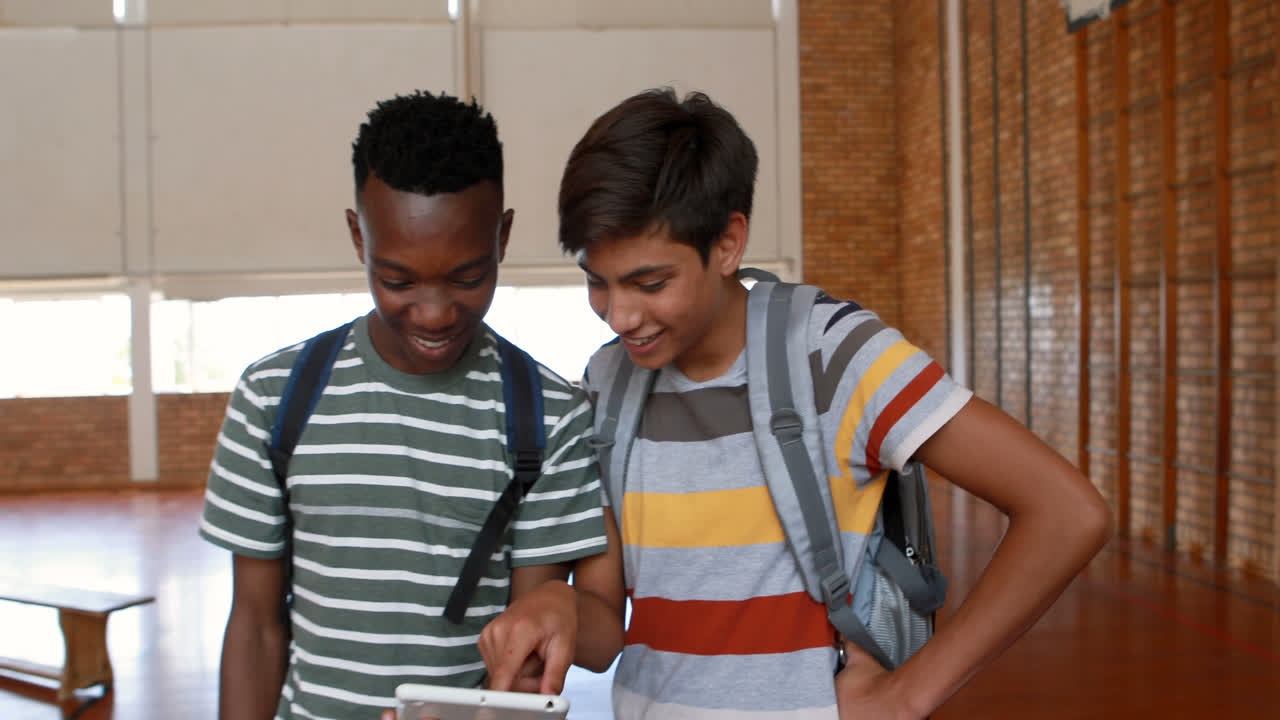 Happy students using digital tablet in basketball court