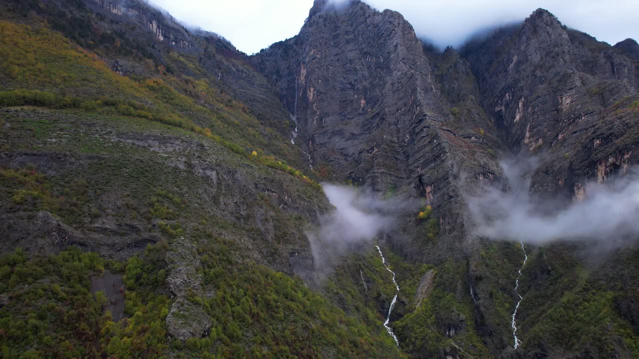 los arroyos fluyen rápidamente por las laderas rocosas de la montaña cubierta de niebla en los alpes albaneses