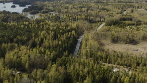 aerial, pan, drone shot revealing a car on a road in the archipelago, on a sunny, spring day, in the saaristo of porvoo, in uusimaa, finland