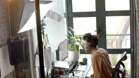 happy african american man at desk making live podcast from home, copy space, slow motion