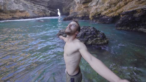 hombre musculoso en acantilados estrellándose contra las olas del mar.