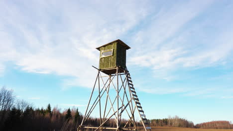 low angle dolly out view of a hunting tower against blue sky