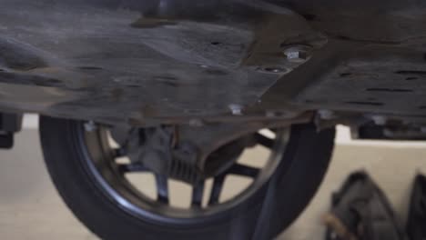 Car-mechanic-working-on-the-car-on-the-lift-in-the-workshop