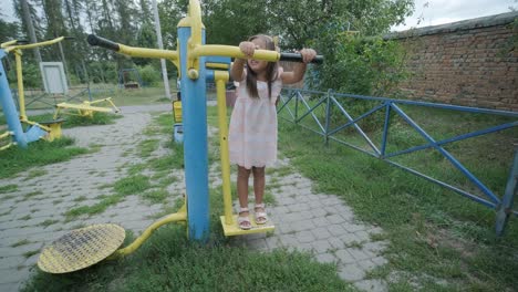 una madre embarazada y su hija joven disfrutan de un tiempo de juego juntos en un patio de recreo en el parque, rodeados de árboles y vegetación
