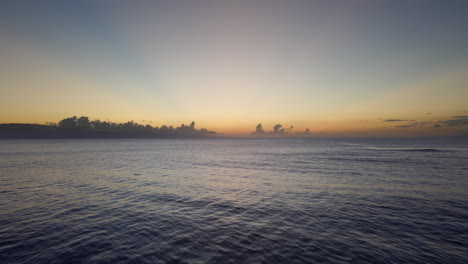 Flying-over-calm-ocean-at-sunset