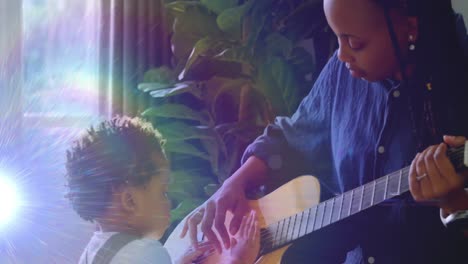 Animation-of-light-flashing-over-african-american-mother-and-son-playing-guitar