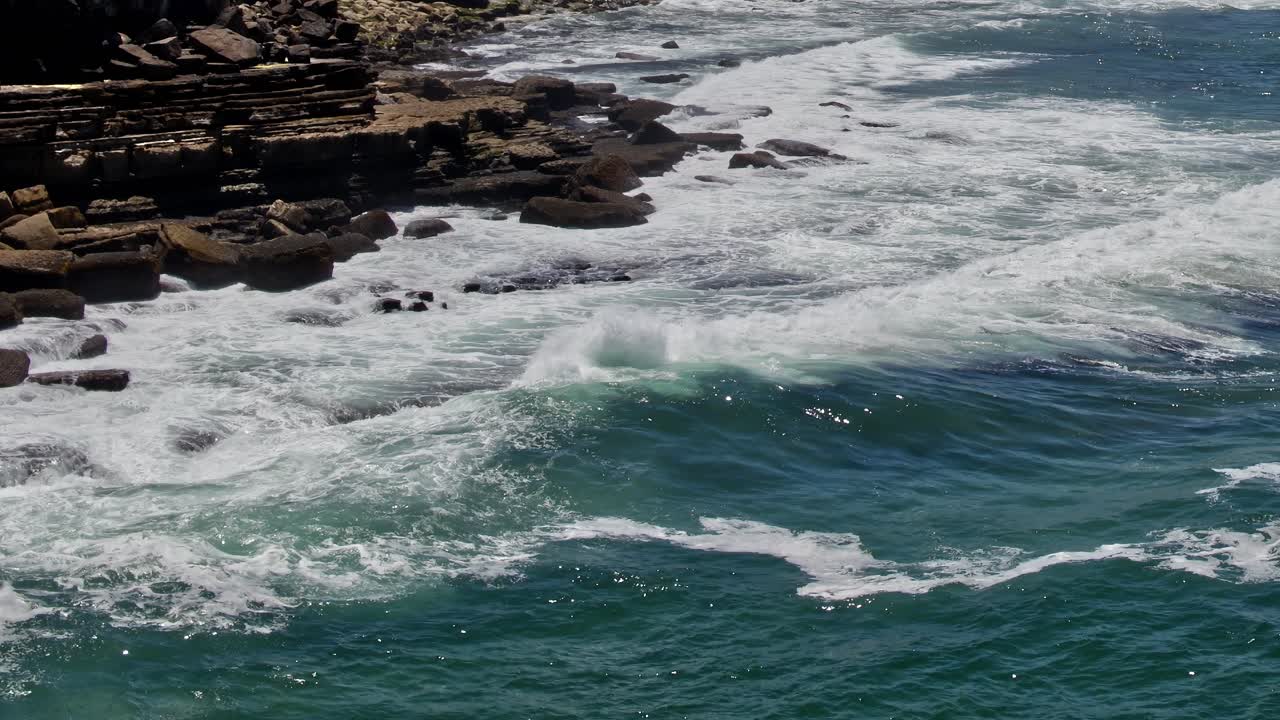 Waves crashing on rocky coastline in Portugal during sunny day