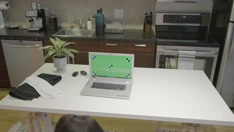 A-static-shot-of-a-black-female-doing-squats-and-curls-with-weights-in-front-of-a-green-screen-lap-top-computer-in-her-kitchen