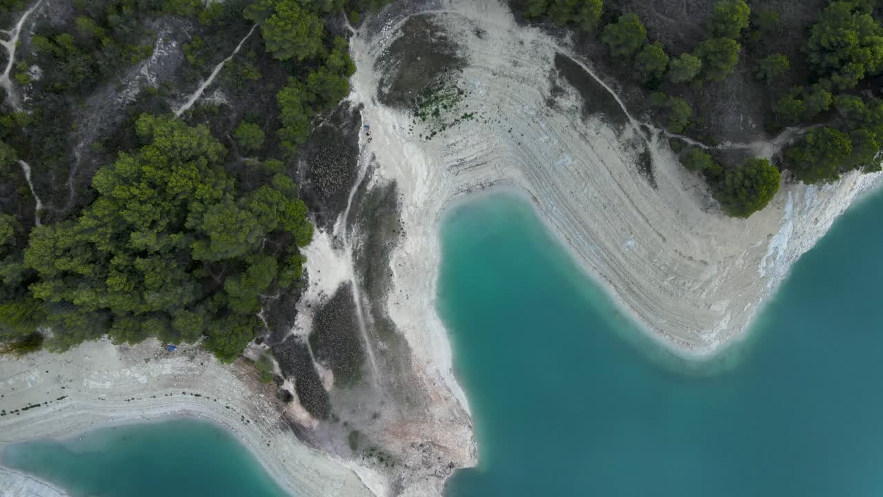 Flygvy över turkos reservoar med frodig skog