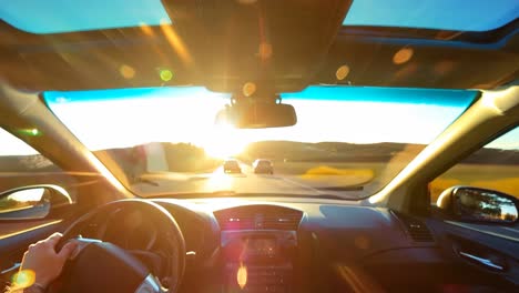 a person driving a car on a road at sunset