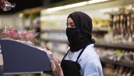 Mujer-Con-Bufanda-Negra-Trabajando-En-La-Tienda,-Inspeccionando-Estantes-En-La-Tienda-En-El-Departamento-De-Panadería