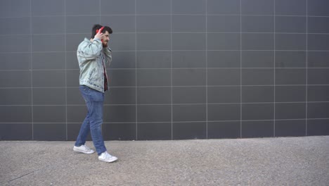 man puts on red headphones and walks while looking at red cell phone