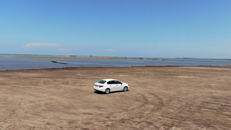 white car driving along the shore of the karavasta lagoon in albania and on a sunny day