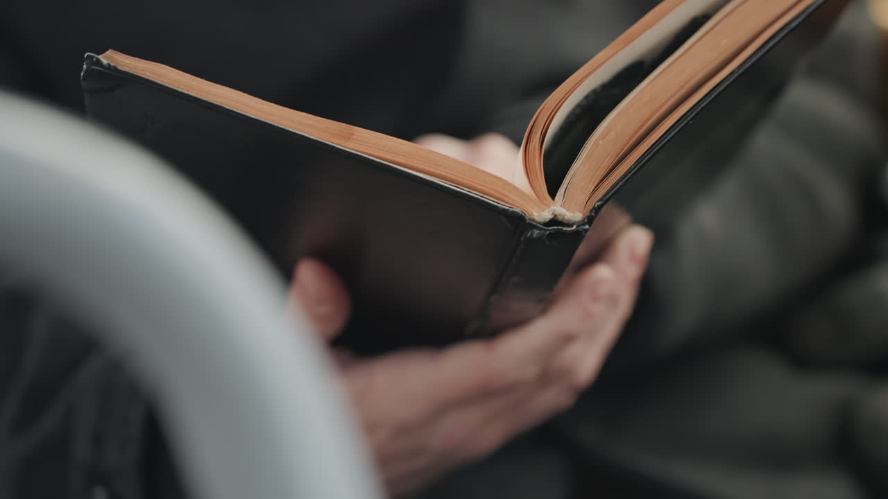 Åbne notesbogssider i hænderne, skaber gennemgår noter og vender sider, brune sidekanter og syet indbinding synlig, nærbillede af fingerspidser og jævn rytme, målrettet pendlerarbejdsstemning.