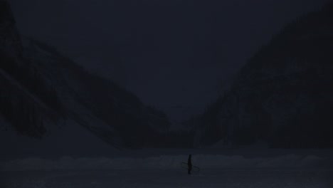 man walking on lake louise on cold winter morning