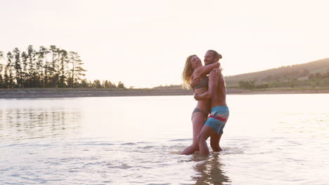 una pareja romántica abrazada en el lago iluminada por el sol de la tarde