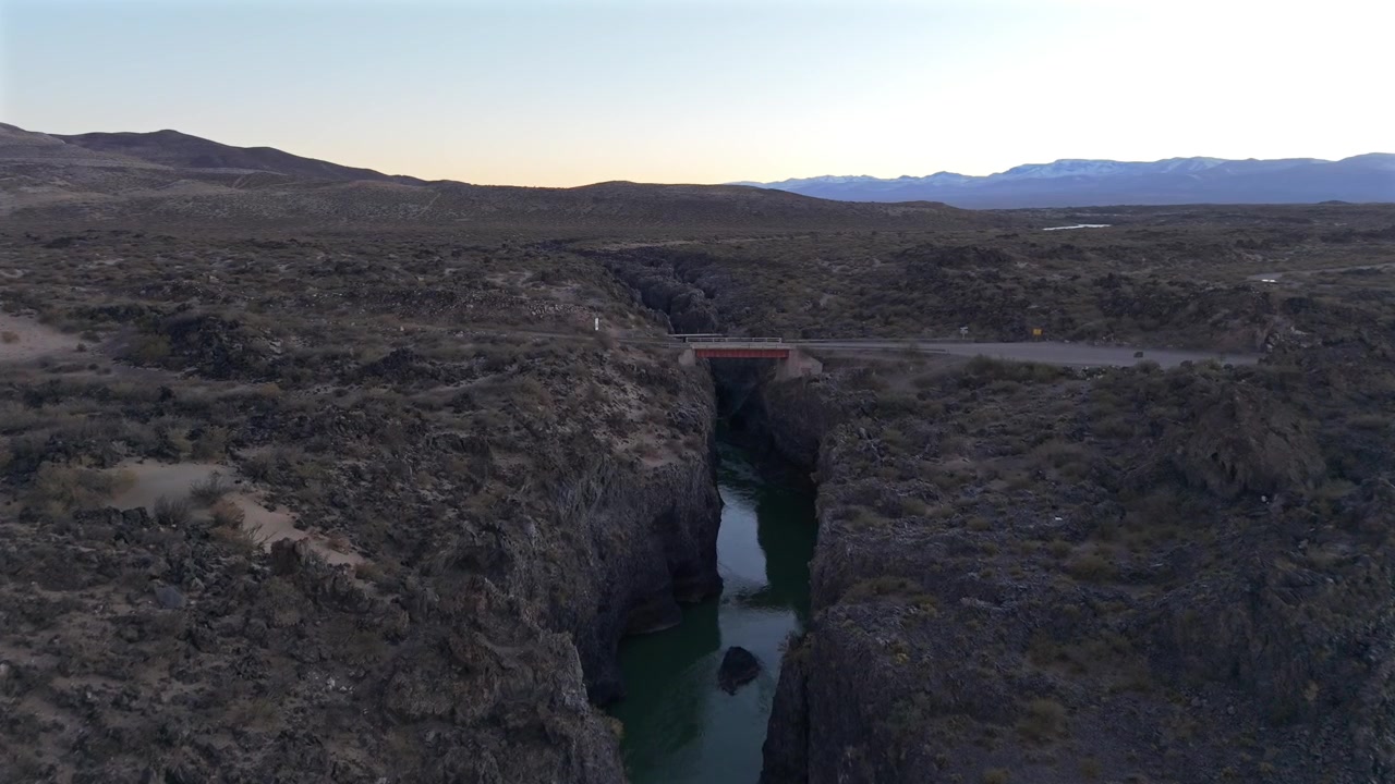 Splendide riprese aeree che sorvolano un profondo canyon fluviale scavato nella roccia vulcanica antica nella Riserva La Payunia, Mendoza, Argentina. Paesaggio desertico arido