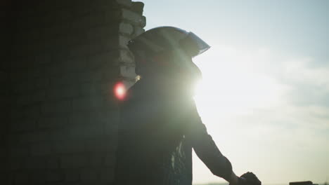 side view of a lady standing by an old building window, her hand resting on the ledge, as she gazes into the distance