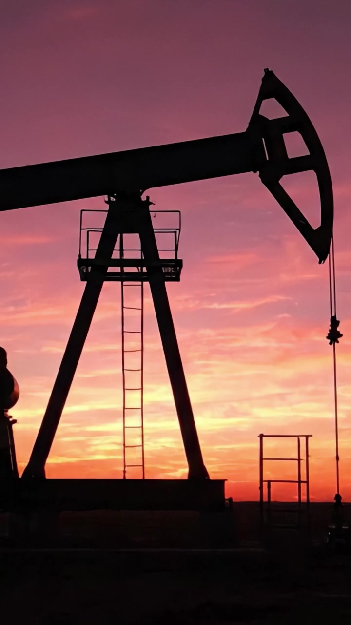 A stunning silhouette of an oil pump jack against a vibrant sunset sky, showcasing the intersection of nature and industrial energy extraction in motion.
