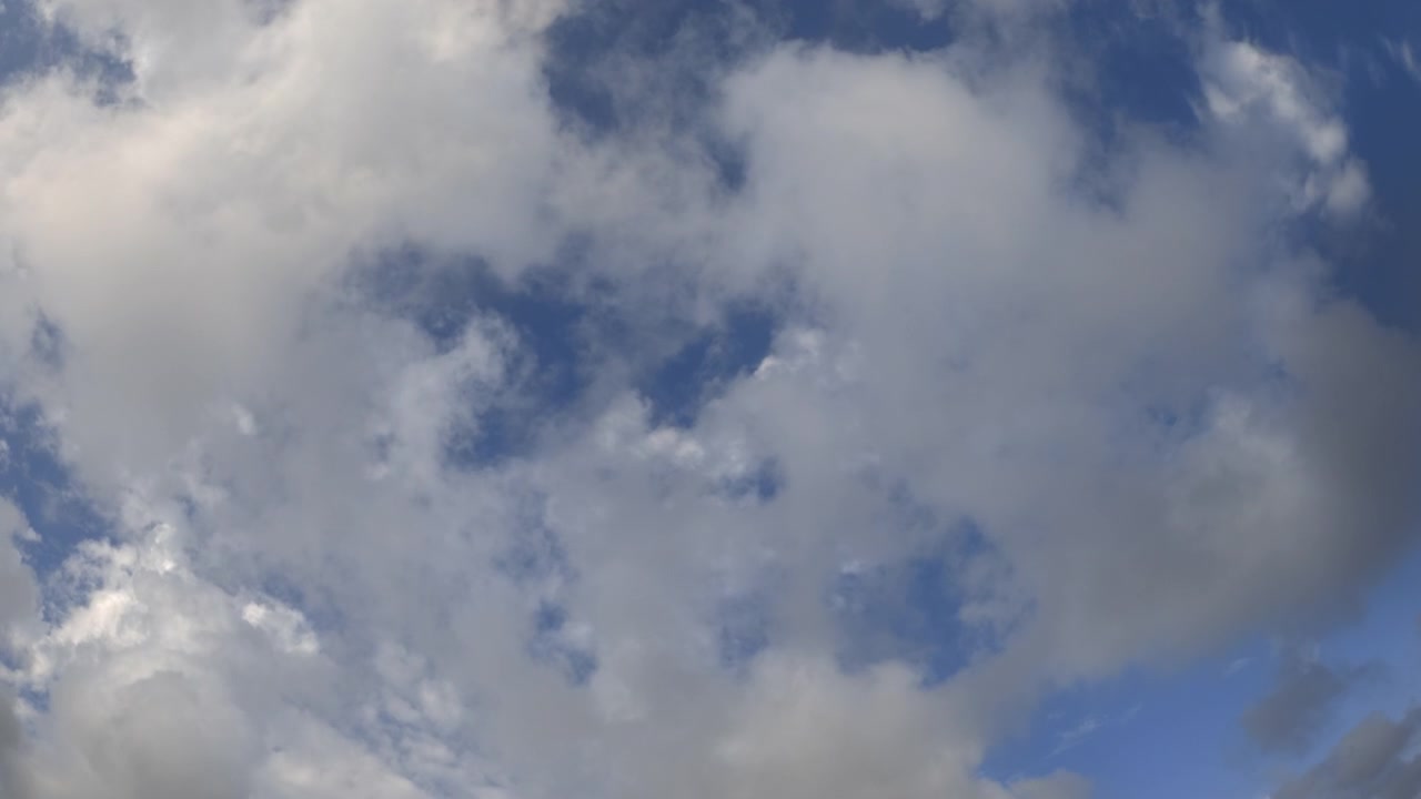 Wide view of white clouds drifting across a blue sky