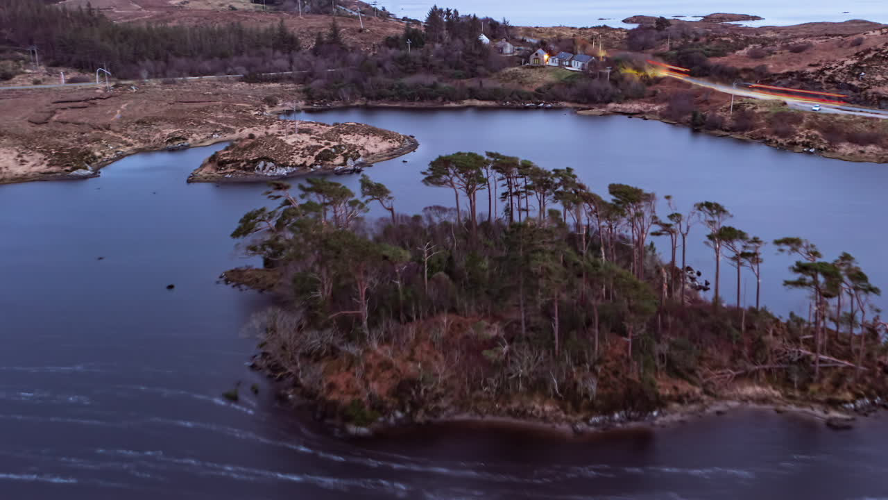 Stop-motion aerial animation at dusk, flying over Pine Island with light trails from Galway road amid Connemara’s lakes