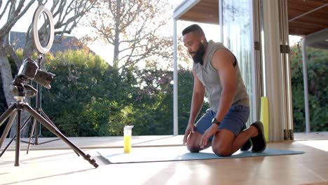vlogger de fitness masculino afroamericano haciendo ejercicio y filmando en casa, cámara lenta