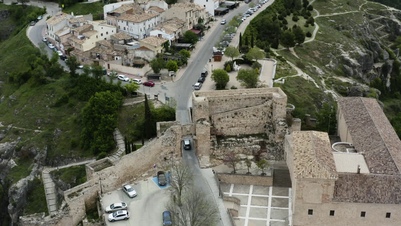 coches pasando por la muralla y el arco de bezudo en la calle trabuco