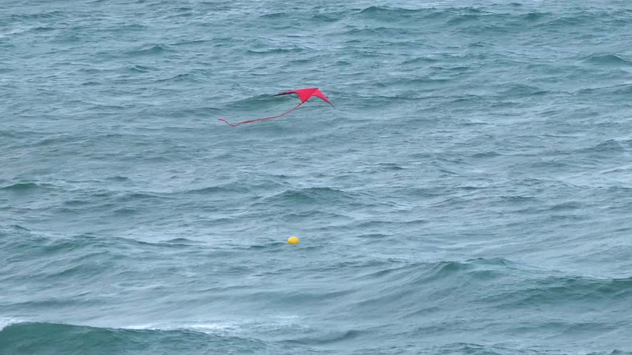 A kite flying on the beach with the sea in the background on a summer day