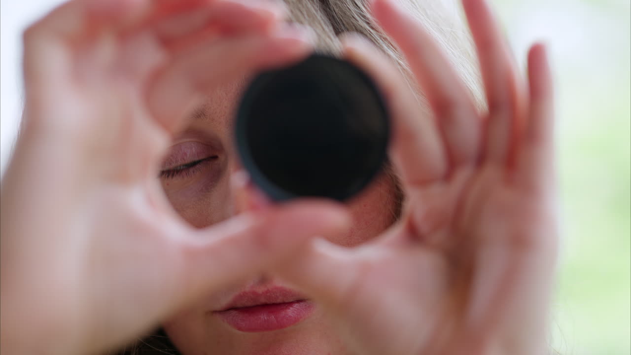Woman looking through camera lens neutral density nd filter while rotating it