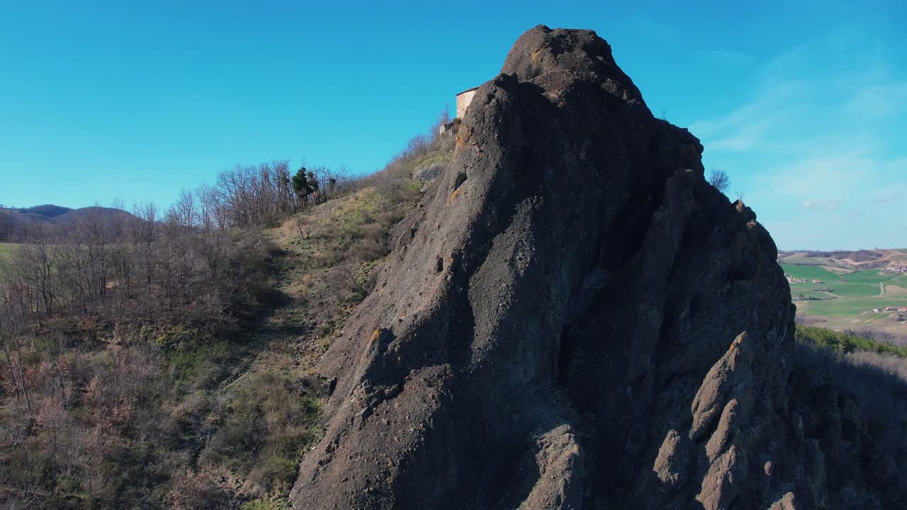 imágenes aéreas de pietra perduca, roca volcánica, iglesia situada en la piedra superior inmersa en el paisaje rural, tierra cultivada en val trebbia bobbio, emilia romagna, italia