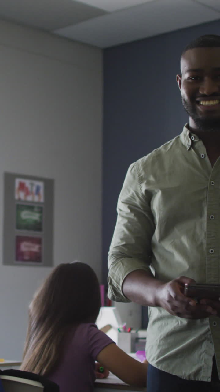 video de un feliz maestro afroamericano de pie en una clase de alumnos diversos