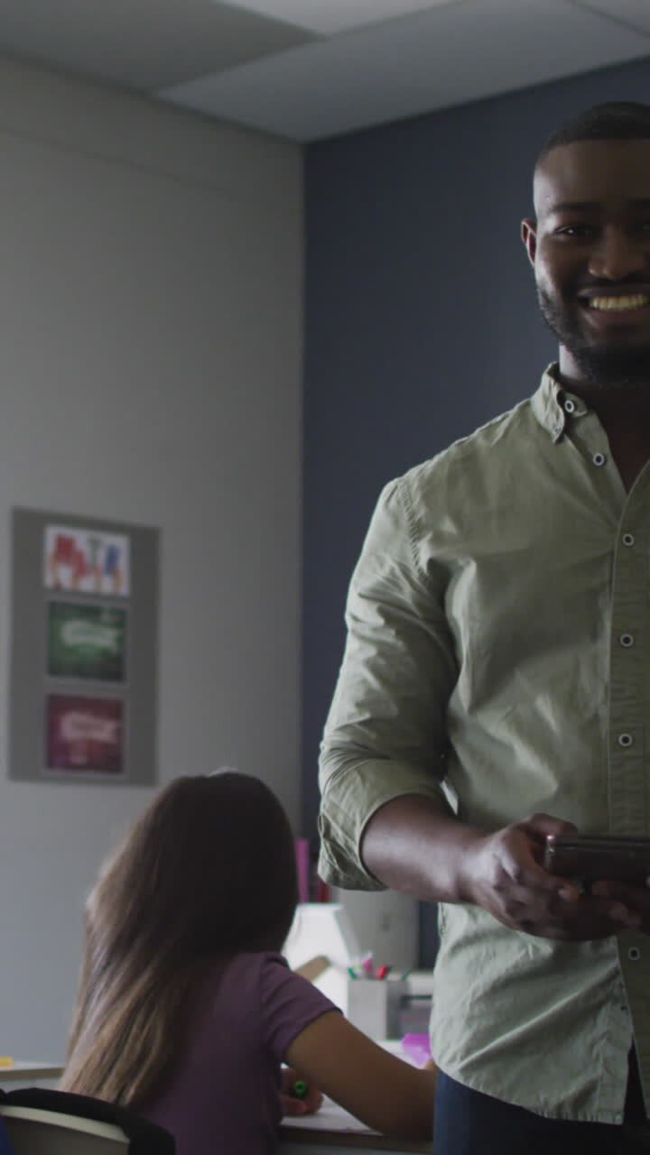 Video of happy african american male teacher standing in class of diverse pupils