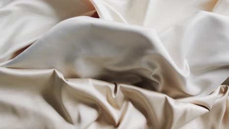 Close-up-of-white-and-beige-shiny-silk-clothes-in-slow-motion