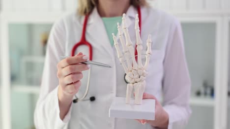 medical professional explaining hand anatomy with skeletal model