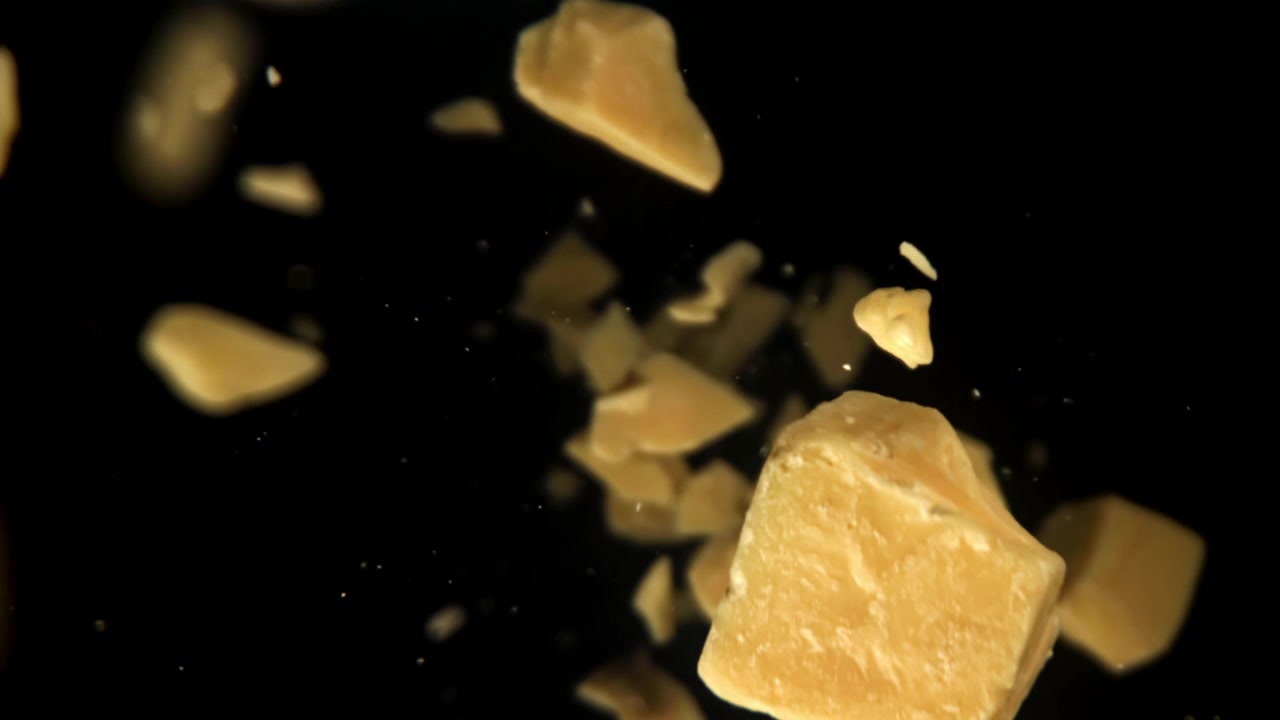 Parmesan Cheese Pieces Falling in Slow Motion on Black Background