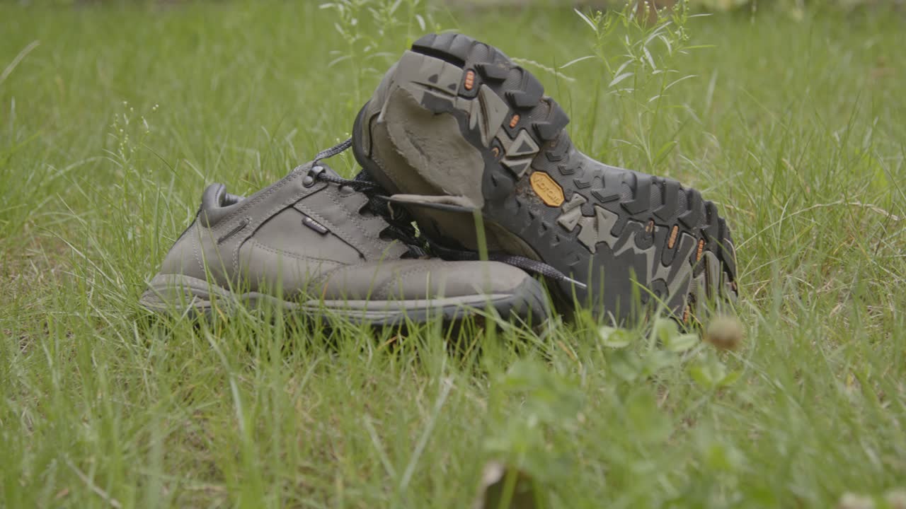 Wide dolly of of worn hiking shoes in a grass field