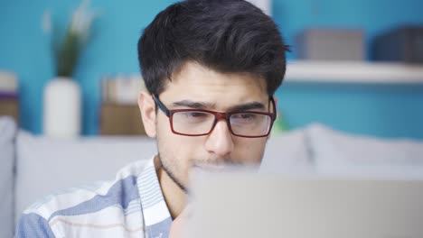 un joven pensativo que trabaja en una computadora portátil encuentra una buena idea.