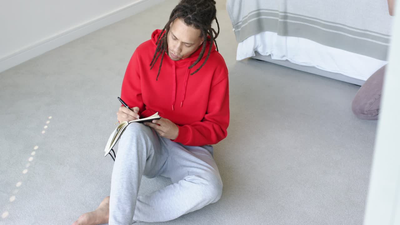 Entrando no plano, homem sentado no quarto abrindo um notebook e escrevendo ideias para organizar os pensamentos
