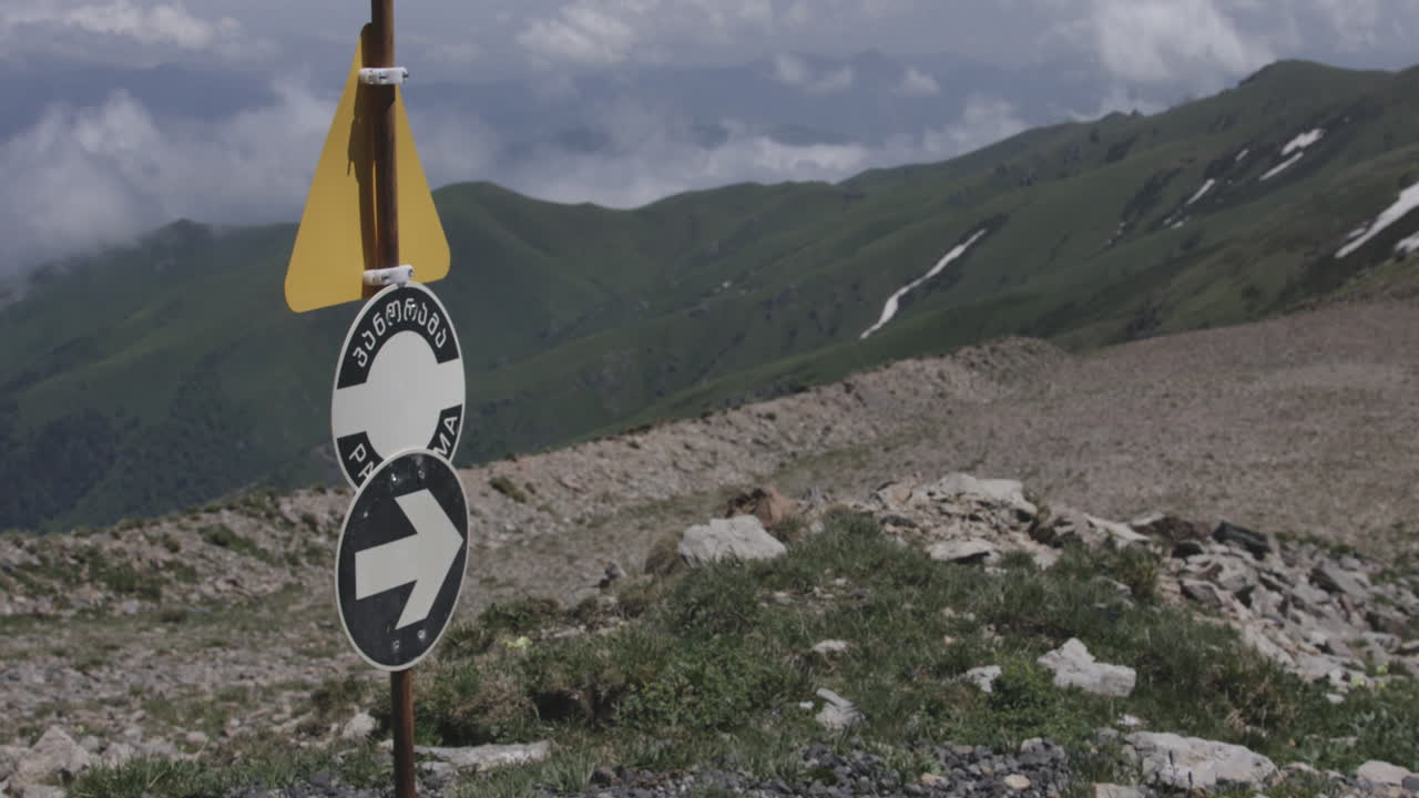 signo de triángulo amarillo y flecha para excursionistas en la cima de la montaña en georgia