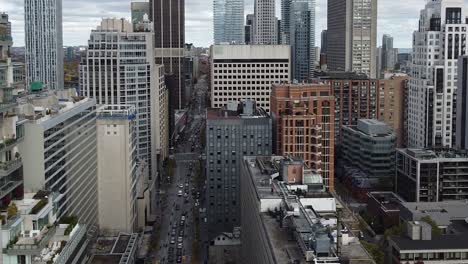 Aerial-of-city-street-surrounded-by-tall-urban-city-commercial-and-residential-building-developments