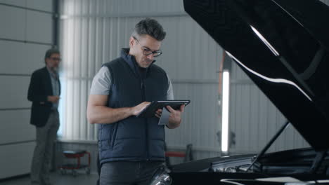 car mechanic using tablet for diagnostics in auto repair shop