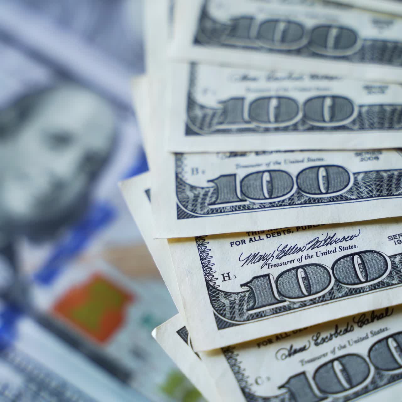 Edges of hundred dollar bills spinning around. Paper money background. American banknotes rotating on dollars background.