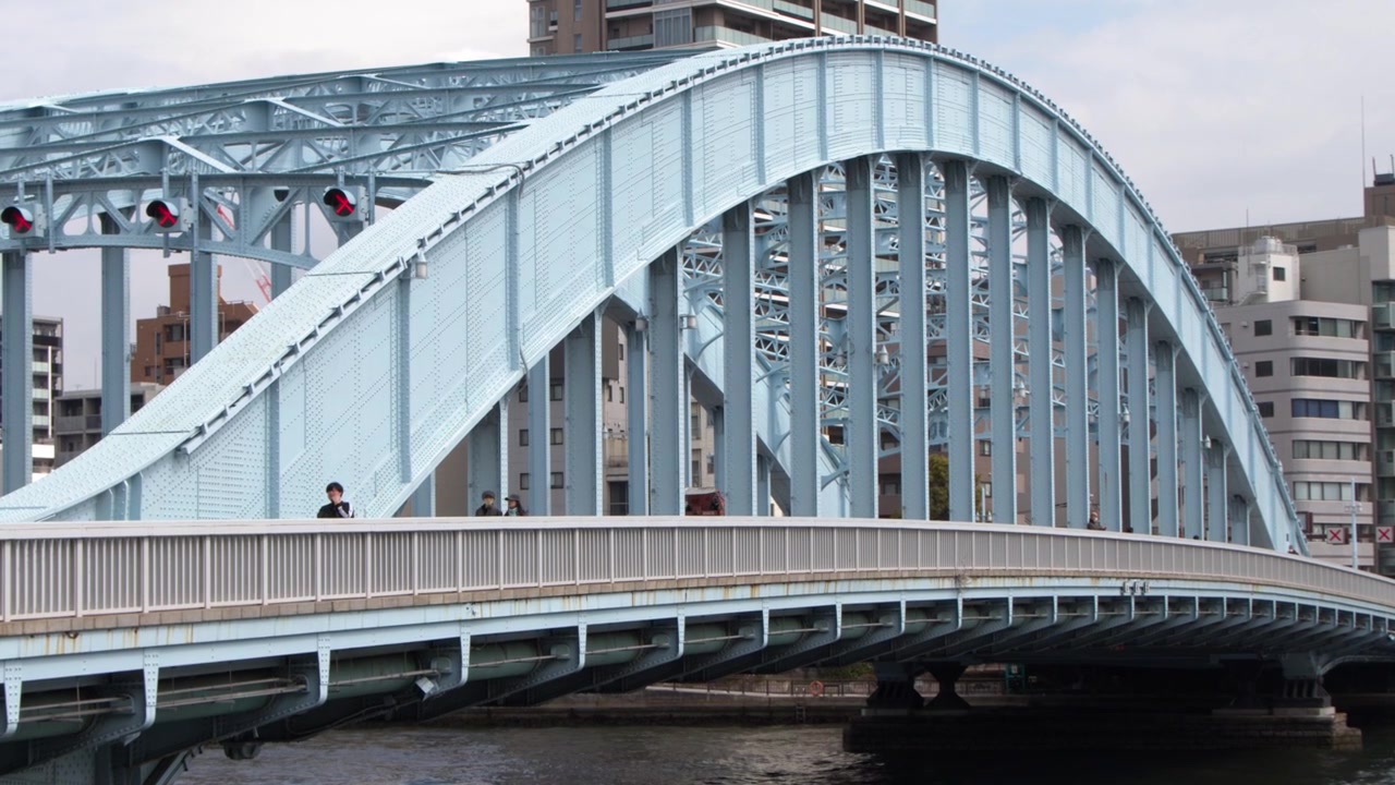 Static wide shot of the blue Eitai Bridge with urban buildings in Tokyo, Japan.