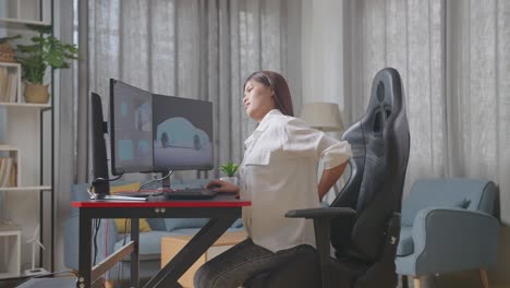 side view of asian female automotive designer having a backache while working on 3d model of ev car on the desktop computers in the studio