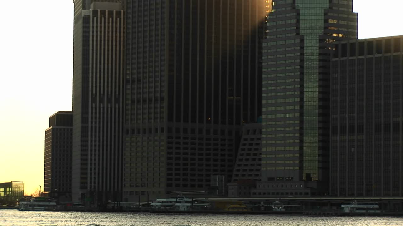 impresionantes rascacielos vistos desde el río hacia el cielo con la luz del sol atrapando la esquina de un edificio en la hora dorada