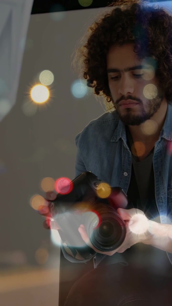 Video verticale: Fotografo uomo che prepara uno scatto, controlla la DSLR, regola l'obiettivo e le ghiere, con effetto bokeh in sovrimpressione.